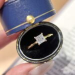 Anel de noivado com moissanita lapidação princesa em ouro 18K e aro torcido.