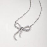 Colar com pingente de moissanita em formato de laço, cravejado com pavé de diamantes. Colar com pingente redondo em formato de laço, cravejado com pavé de moissanita.