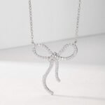 Colar com pingente de moissanita em formato de laço, cravejado com pavé. Colar com pingente redondo em formato de laço, cravejado com pavé de moissanita.