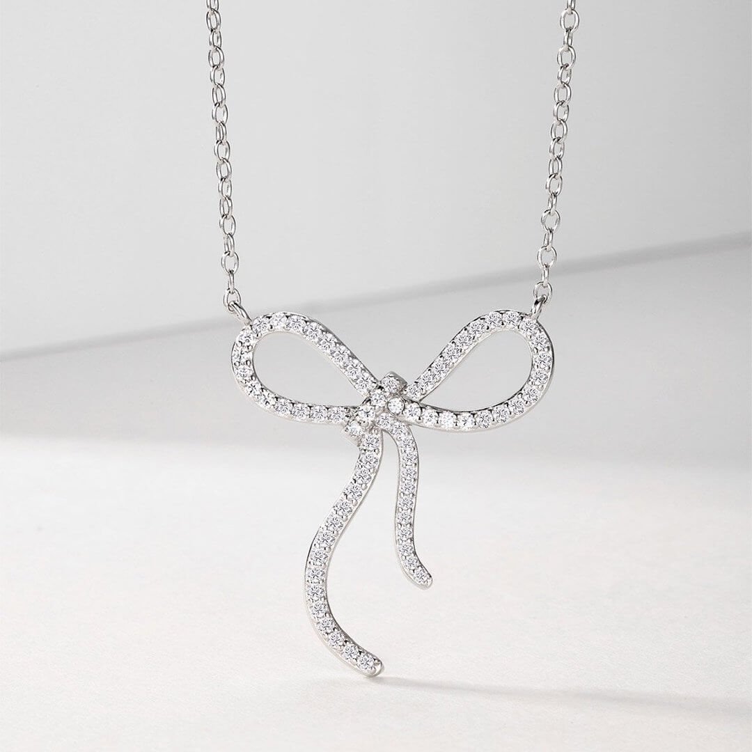 Colar com pingente redondo em formato de laço, cravejado com pavé de moissanita. Colar com pingente redondo em formato de laço, cravejado com pavé de moissanita.